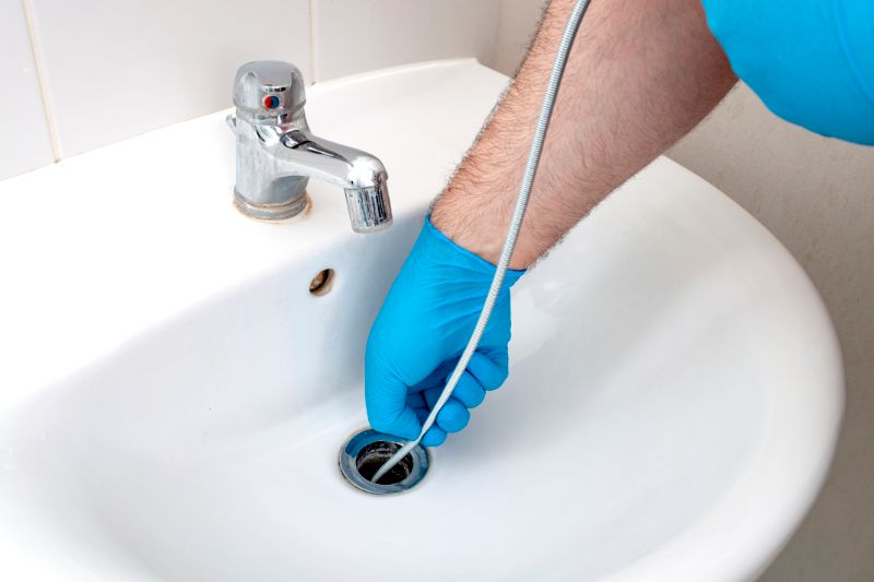 Image of someone snaking a drain. Why Do My Drains Keep Clogging?